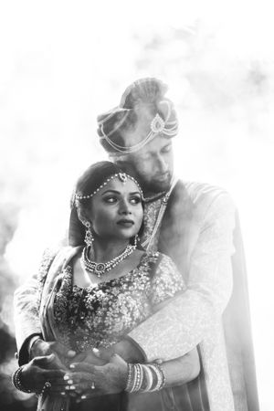 Dramatic black and white portrait of South Asian couple at Sheraton Parsippany Hotel, surrounded by ceremonial smoke after wedding rituals.