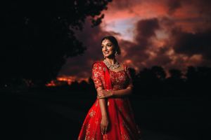 Stunning South Asian bride at sunrise in a red lehenga, captured at Springfield Country Club with a dramatic sky backdrop.