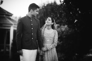 Romantic black and white portrait of a South Asian couple walking at The Marigold in Somerset, NJ, sharing a joyful, candid moment.