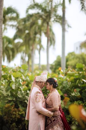 Romantic South Asian wedding portrait at Hard Rock Punta Cana, with couple embracing amid palm trees and tropical greenery.