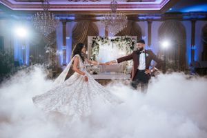 Bride and groom share a magical first dance at Lucien's Manor, surrounded by fog, chandeliers, and elegant South Asian wedding decor.