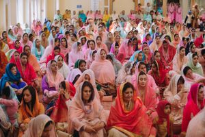 Colorful Sikh wedding ceremony with women in vibrant traditional attire gathered in prayer, captured in a joyous and spiritual moment.