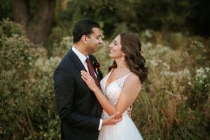 Romantic wedding portrait at Springfield Country Club with the couple embrace in a lush garden setting filled with greenery and wildflowers