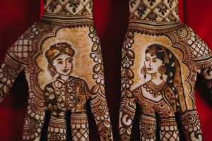 Intricate bridal mehndi design featuring bride and groom portraits on palms, showcasing traditional South Asian wedding artistry.
