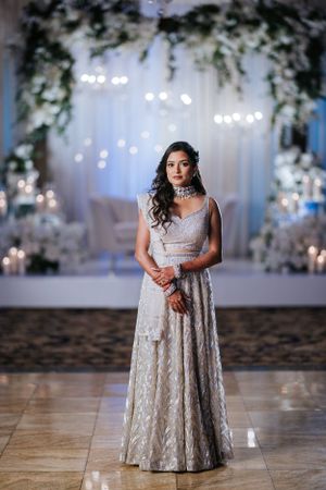 Elegant South Asian bride posing at Lucien's Manor in Berlin, NJ, during a wedding reception with dreamy lights and floral decor.