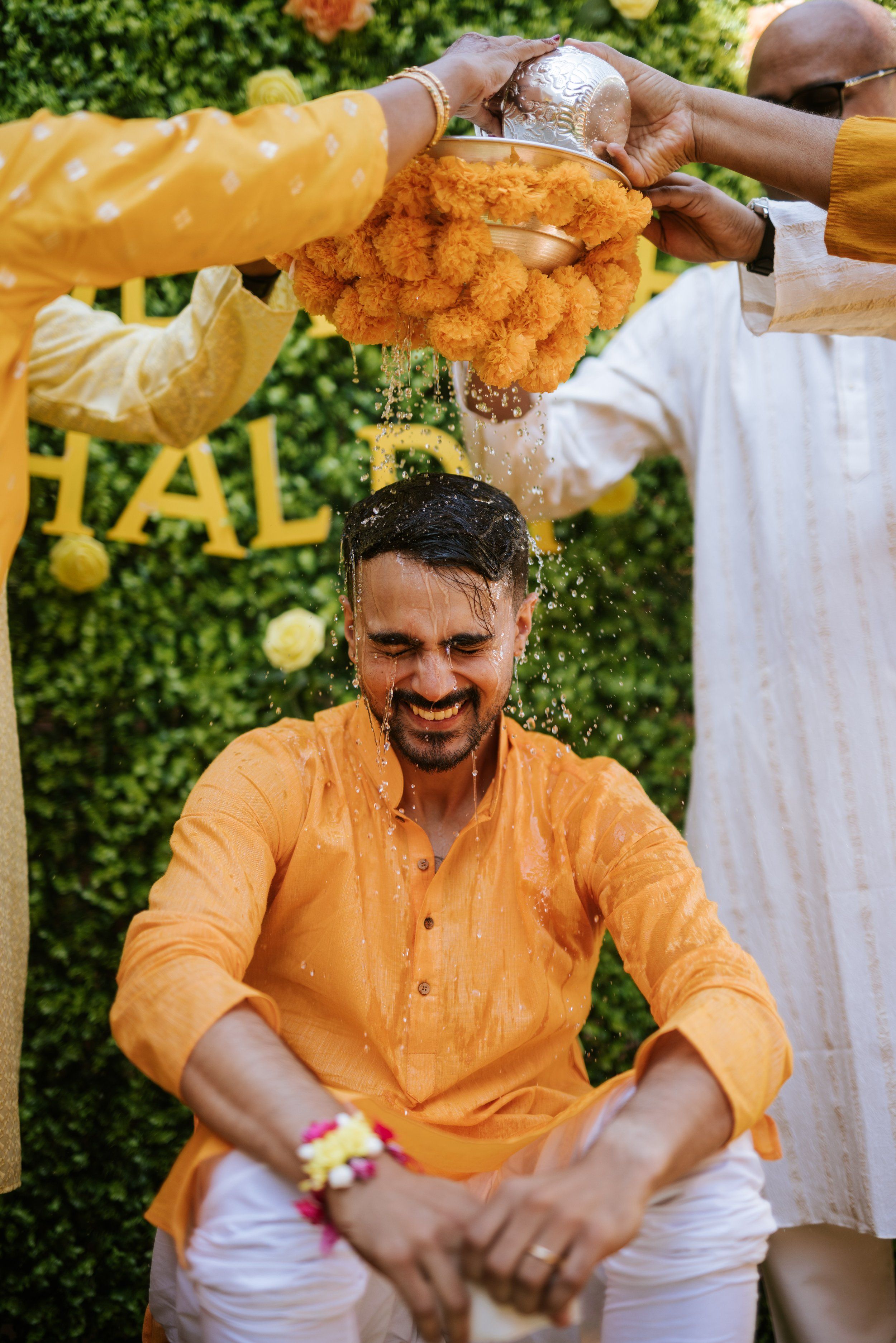 Groom enjoying his Haldi ceremony at The Imperia in Franklin, NJ, dressed in yellow and surrounded by festive floral decor.