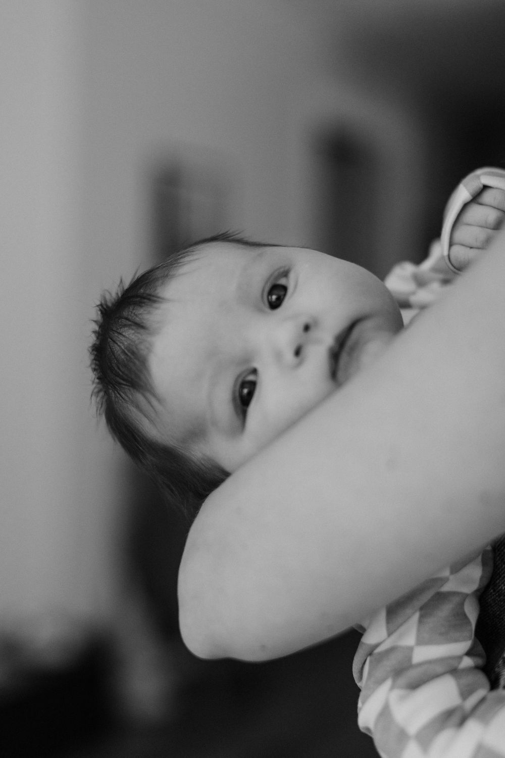 Close-up black and white portrait of a baby looking up with curious eyes.