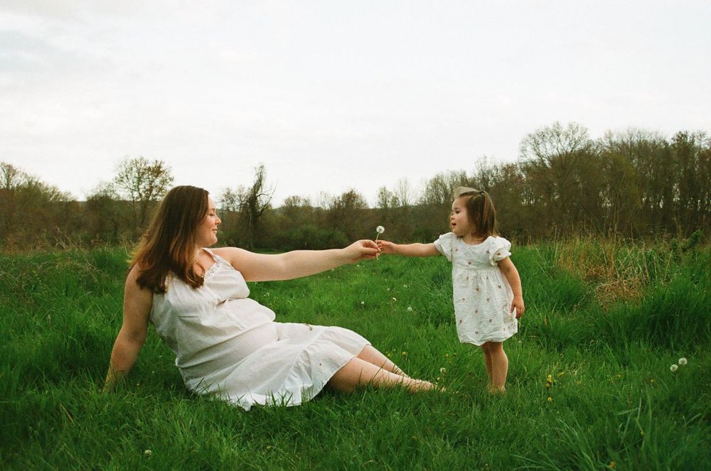 A touching moment between mother and daughter as they play in a sunlit meadow.