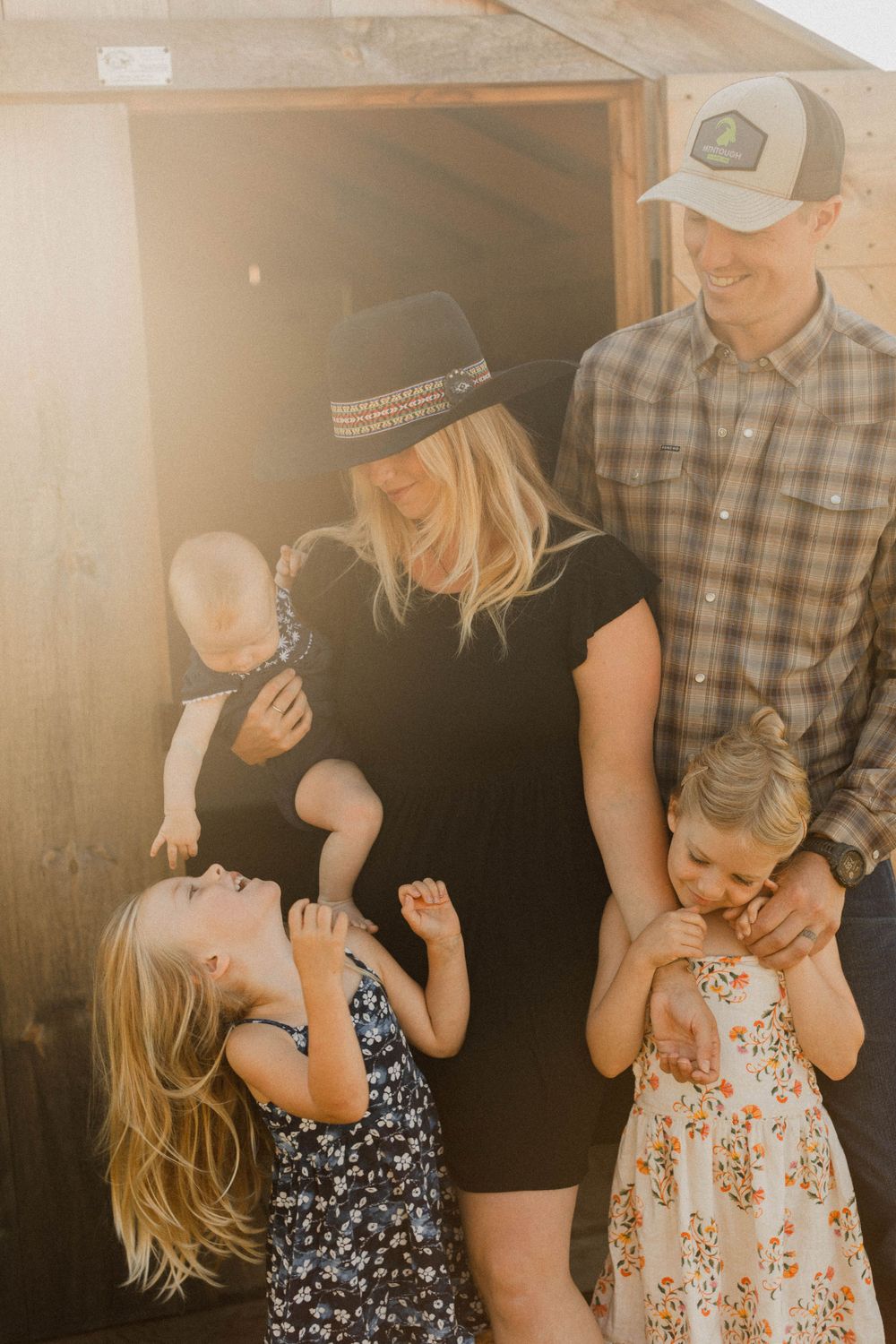A family shares playful moments together in a warmly lit doorway.