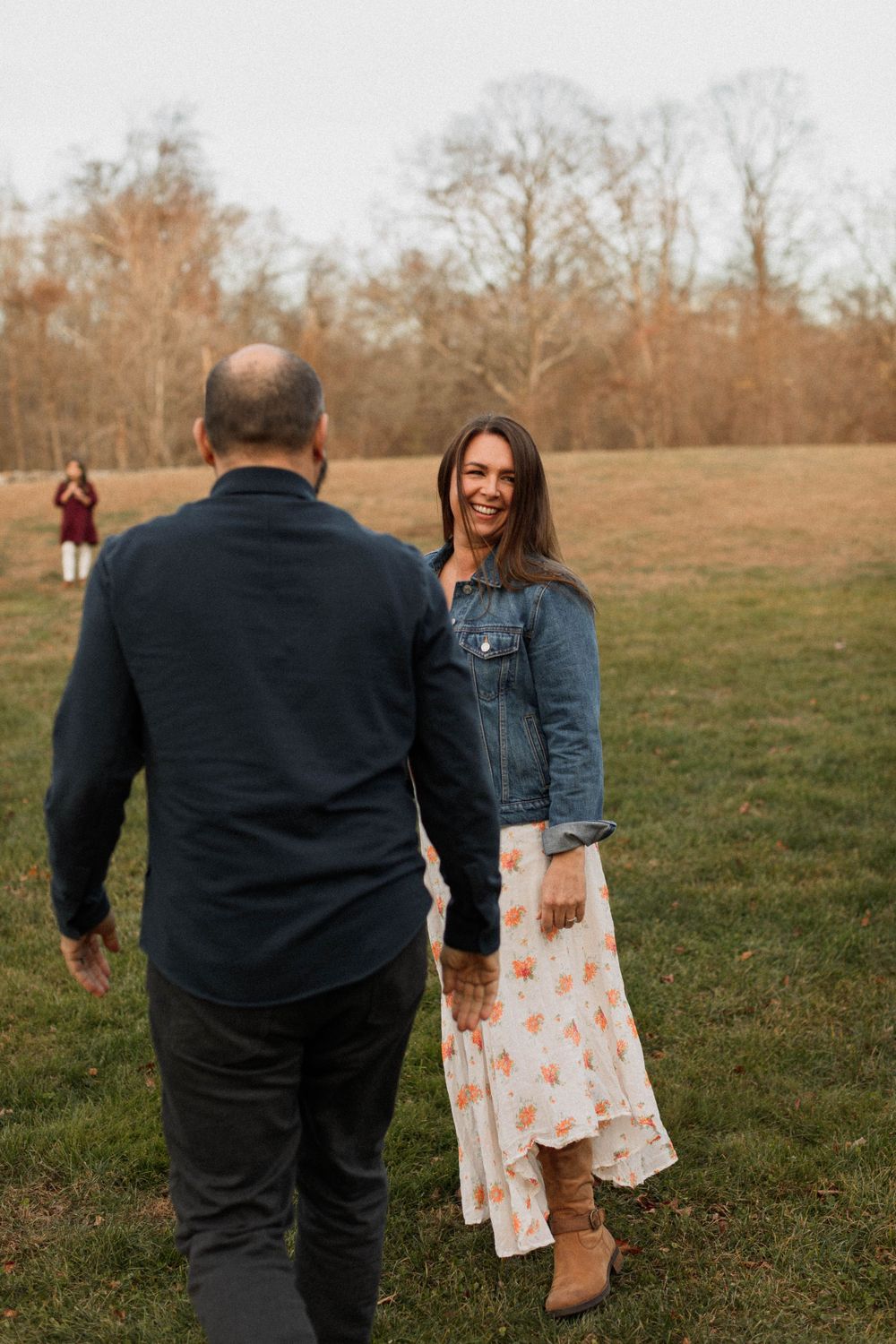 Couple sharing candid moment during outdoor autumn photoshoot in open field.