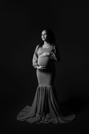 Dramatic black and white maternity portrait in elegant floor-length gown.