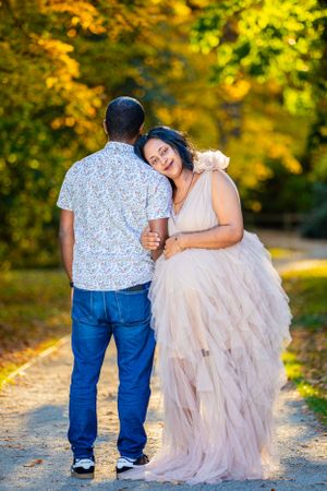 A couple shares a romantic moment on a path surrounded by golden fall leaves.