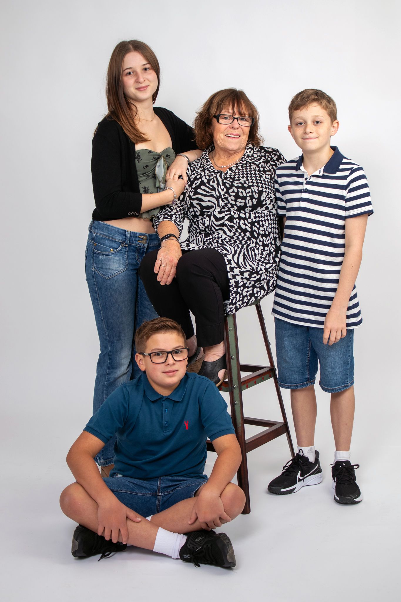 A family poses for a portrait with one person seated on a stool while others stand around.