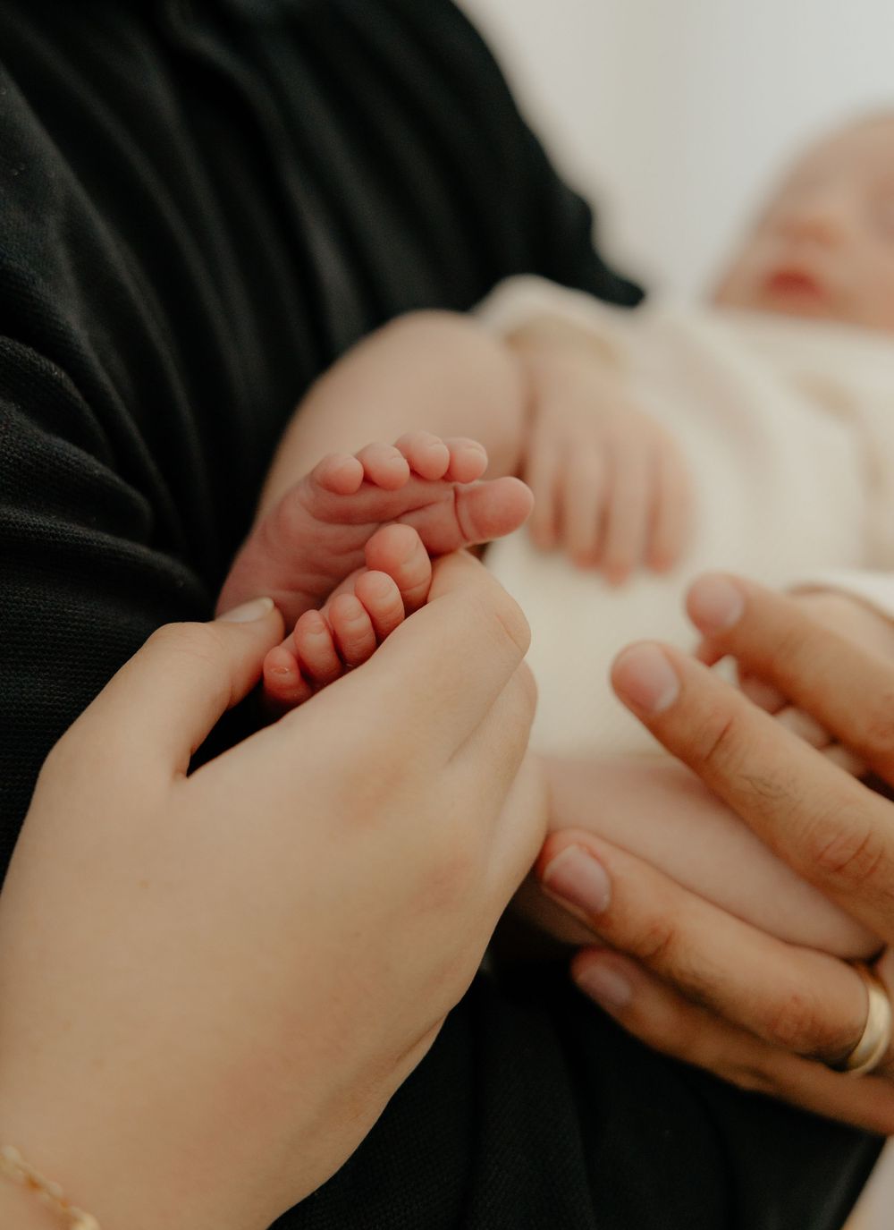 Close-up of mother touching tiny newborn baby feet while infant rests in fathers arms.