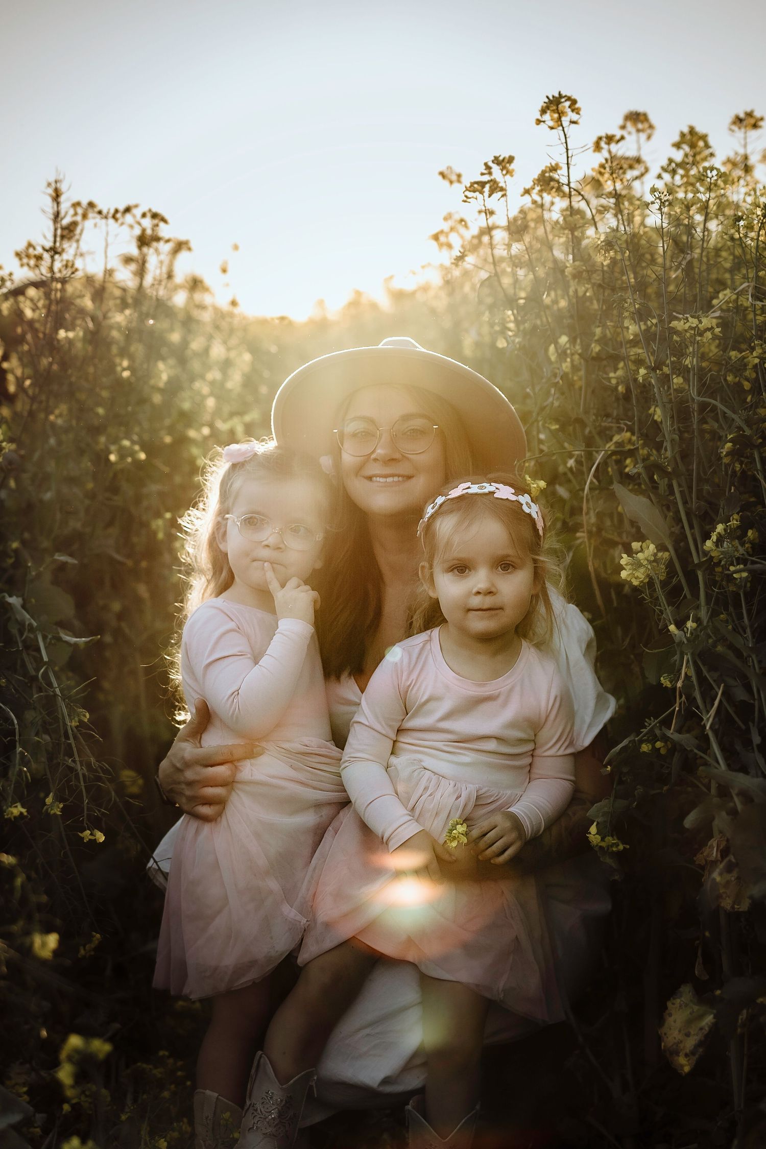 A heartwarming family portrait taken at sunset in a field of wildflowers with golden sunlight streaming through the plants. Gippsland.
