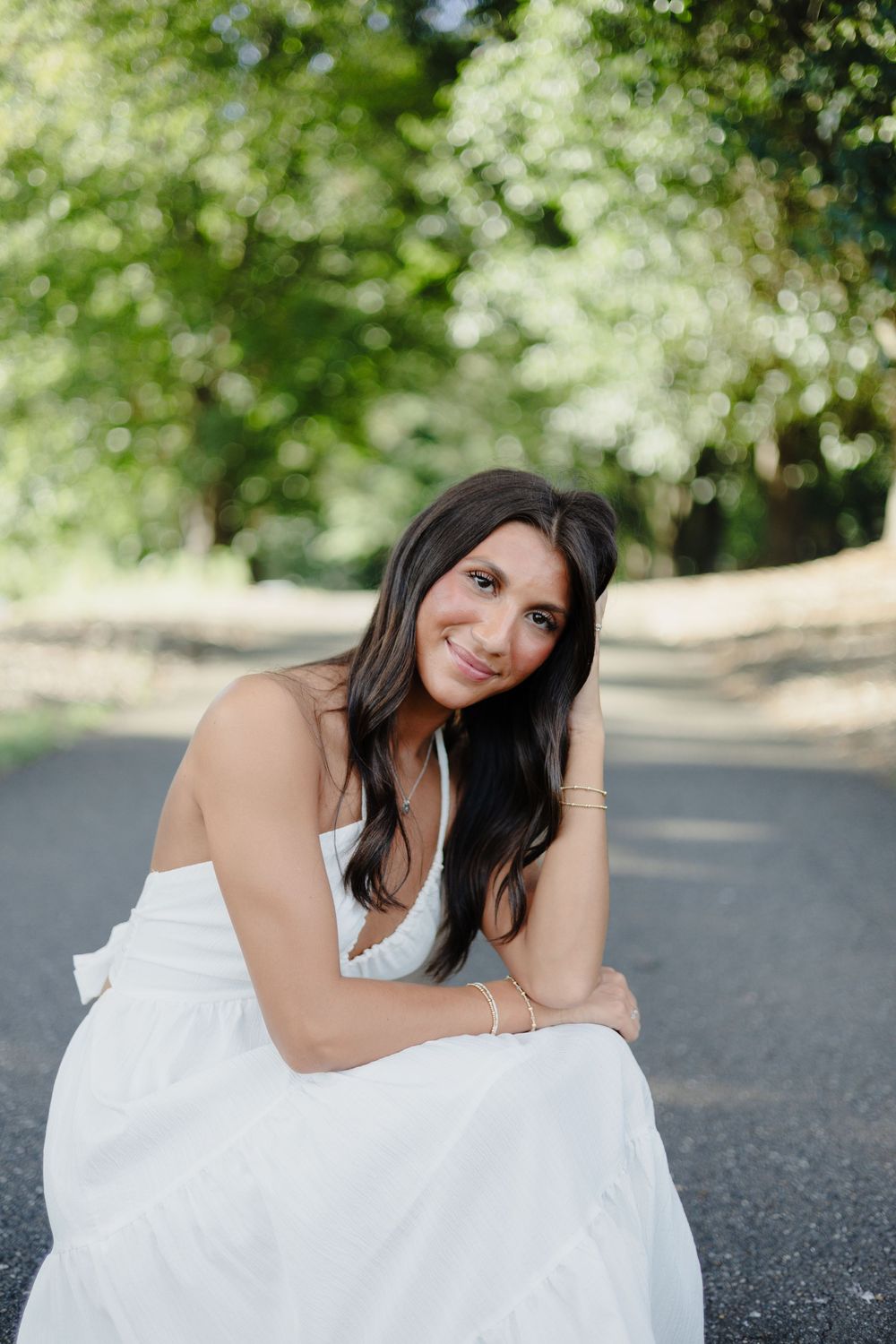 A woman in a white dress poses gracefully on the ground in a series of outdoor portraits.
