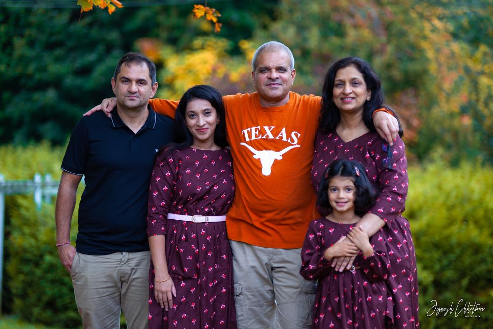 Mom and dad with their daughter and son-in-law, sharing a joyful moment during a fall outdoor photoshoot, surrounded by the golden glow of a