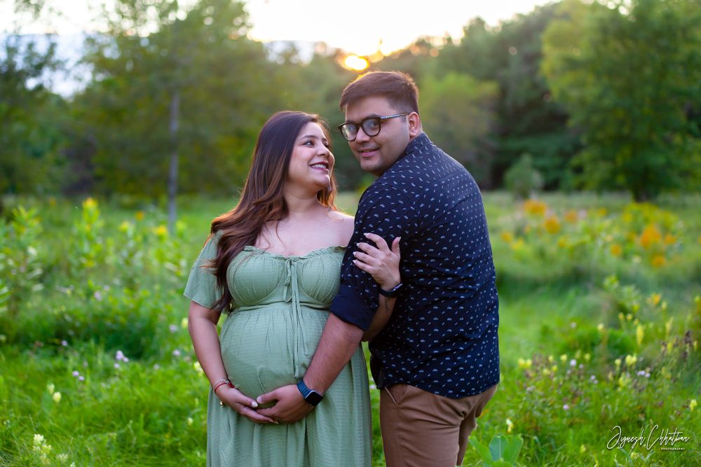 Husband and wife celebrating their pregnancy with a heartfelt outdoor photoshoot, surrounded by the beauty of nature and the warm glow of au