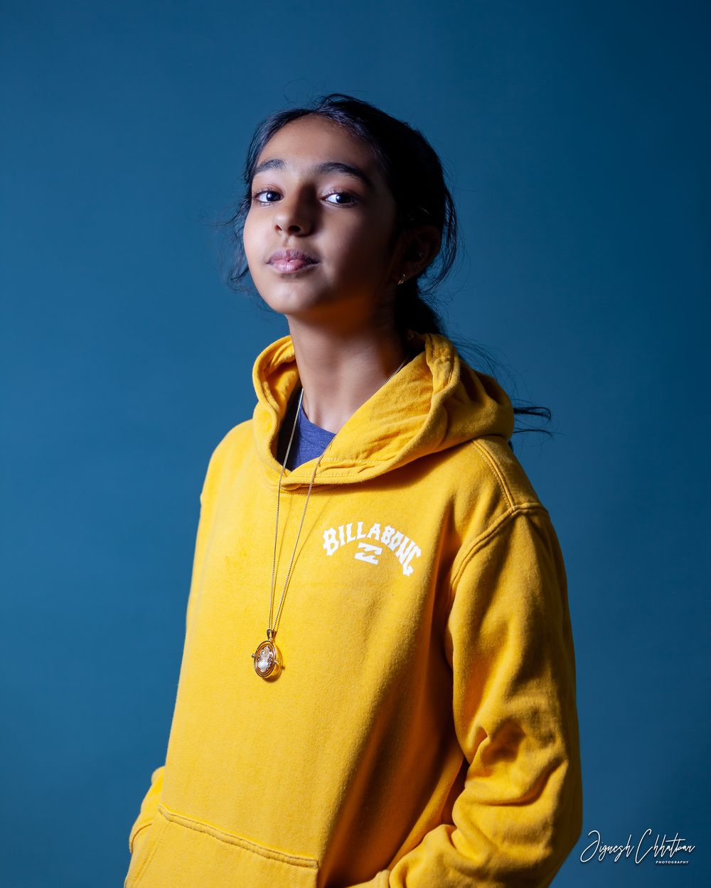 Portrait of a girl with a dramatic expression, set against a striking blue background, highlighting her features with a bold and artistic fl