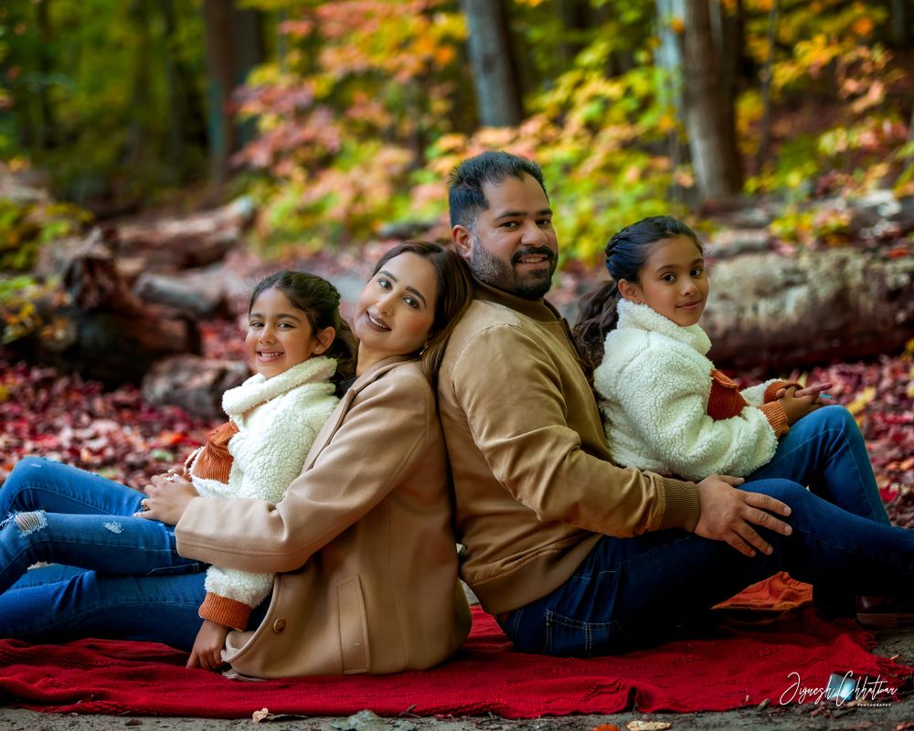 Family of four enjoying a fun outdoor fall photoshoot, with two girls playfully posing among the vibrant autumn leaves, capturing the warmth