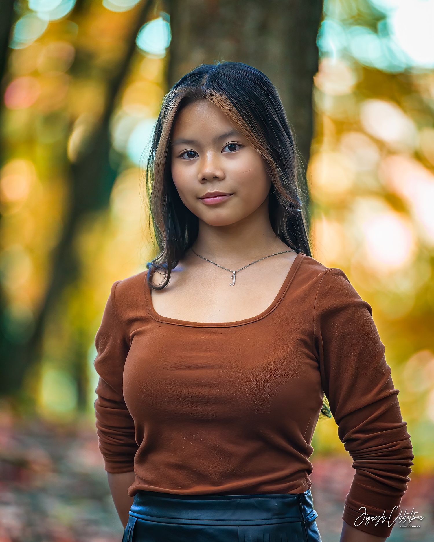 Outdoor portrait of a young, beautiful girl, radiating confidence and elegance against a natural, scenic backdrop.