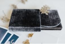 Grey velvet book cover decorated with a delicate golden ornament on white background.