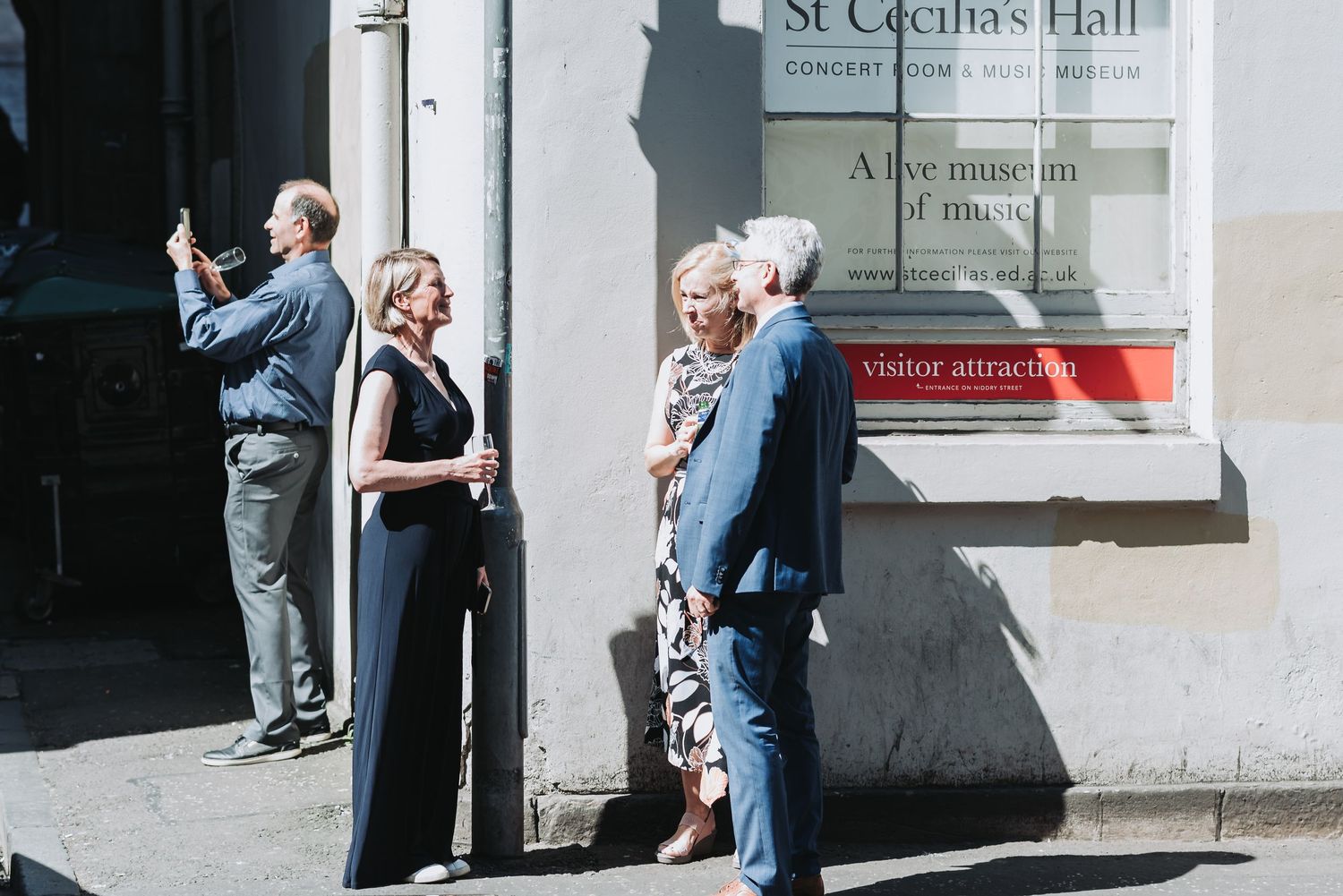 People gathered outside St Cecilia's Hall entrance on a sunny day.