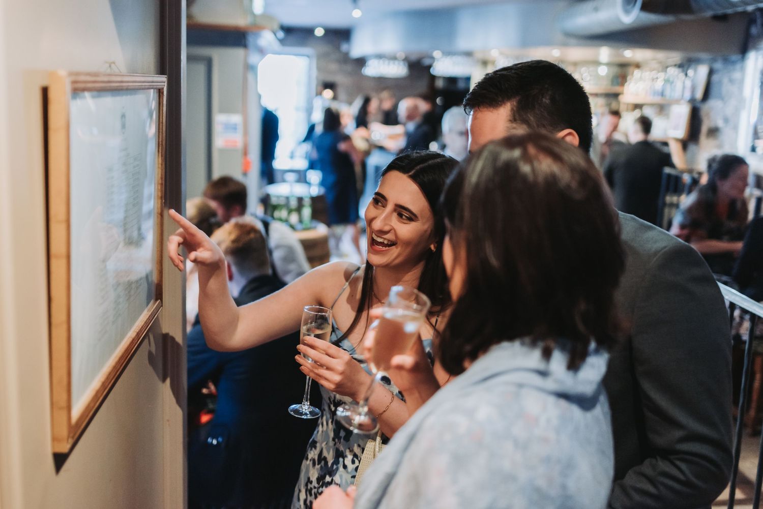 Group of guests pointing and looking at something on the wall during an event.