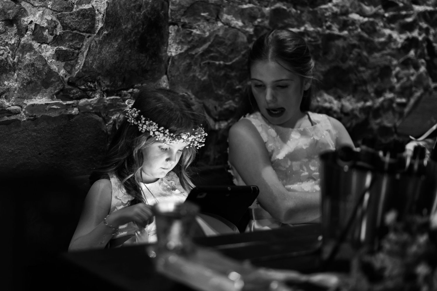 Two children in formal attire sitting at a dimly lit table.