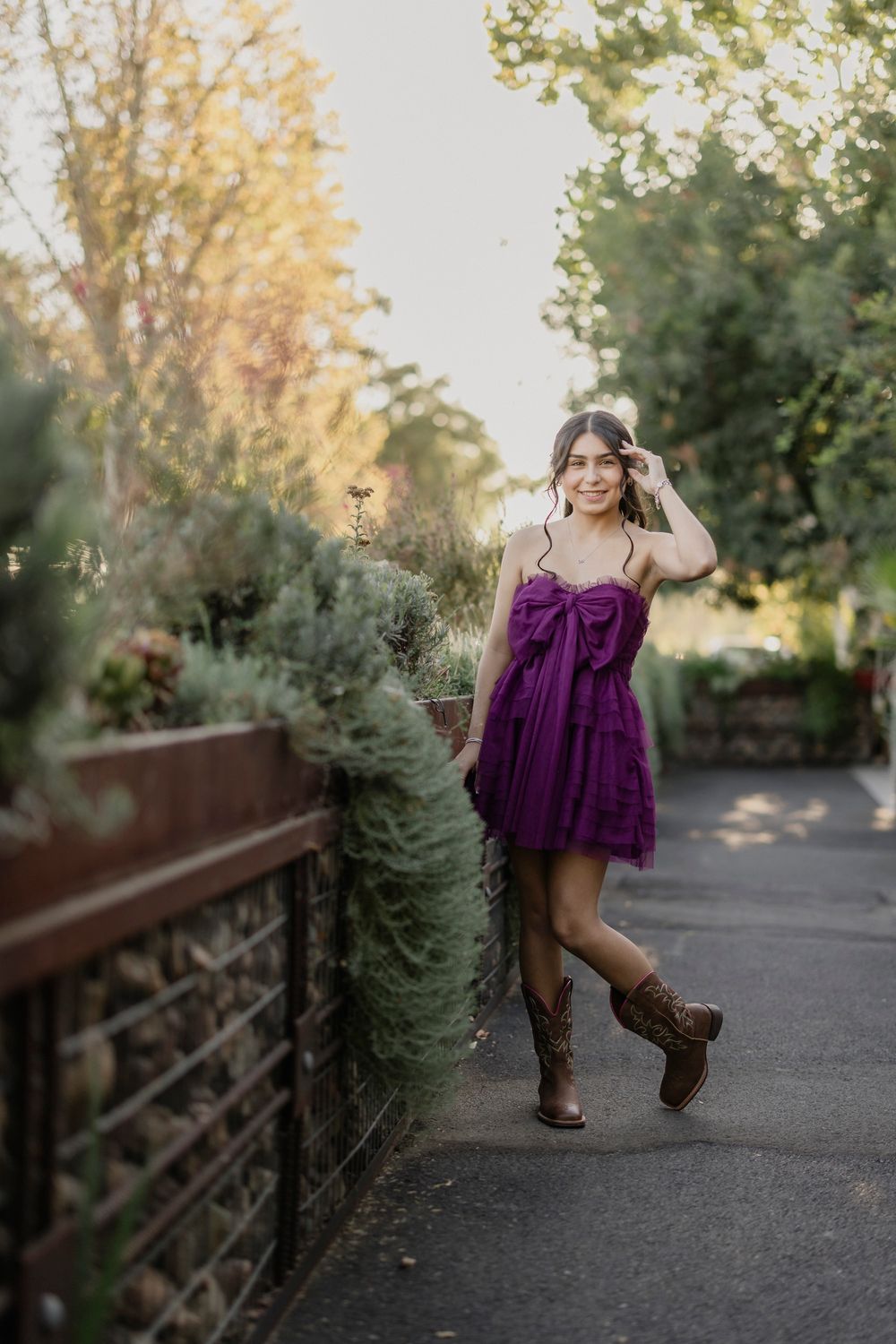 Autumn garden photoshoot featuring purple dress and western boots along stone pathway.