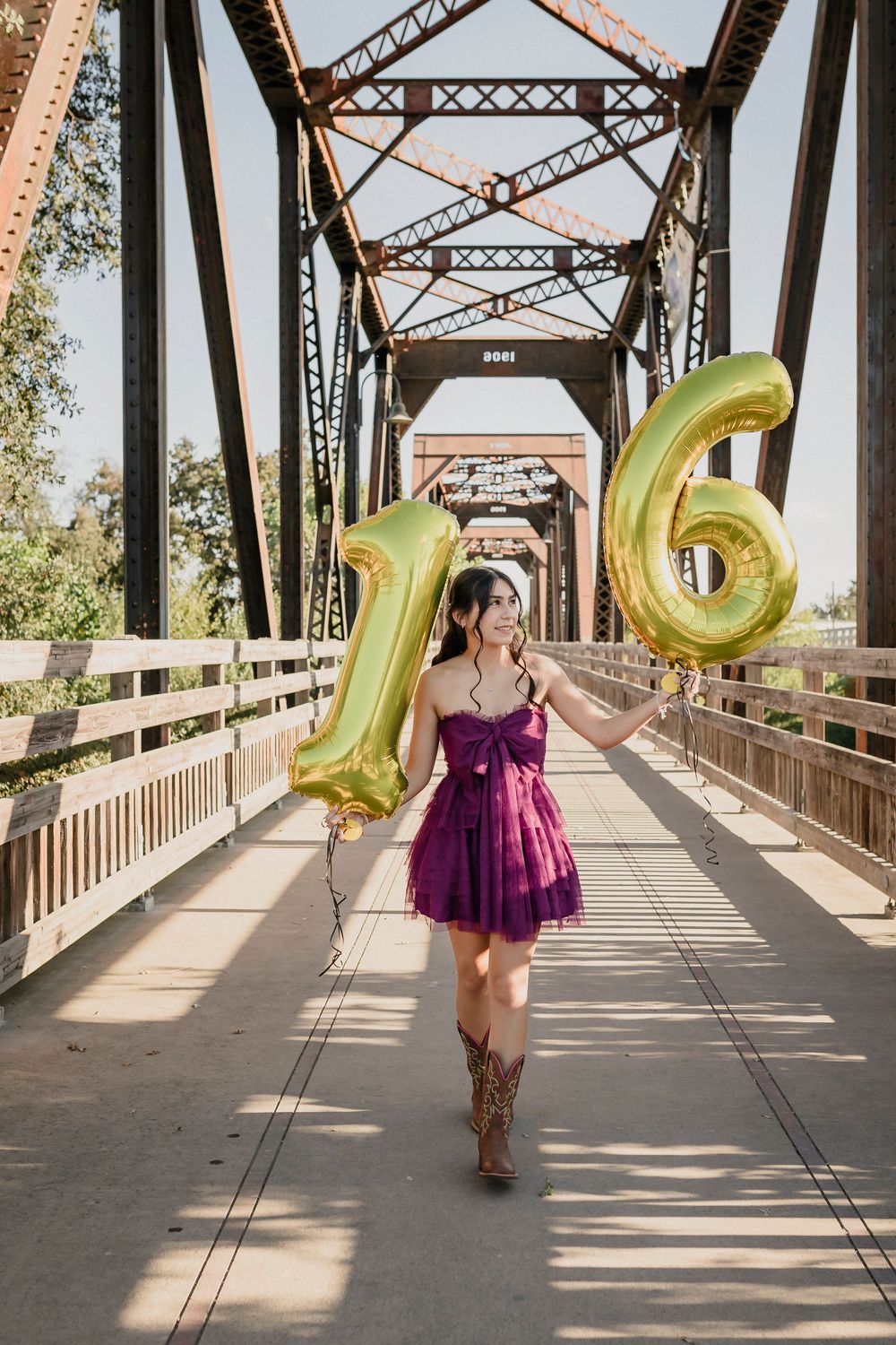 Celebratory photo with gold 16 balloons on a vintage steel bridge structure.