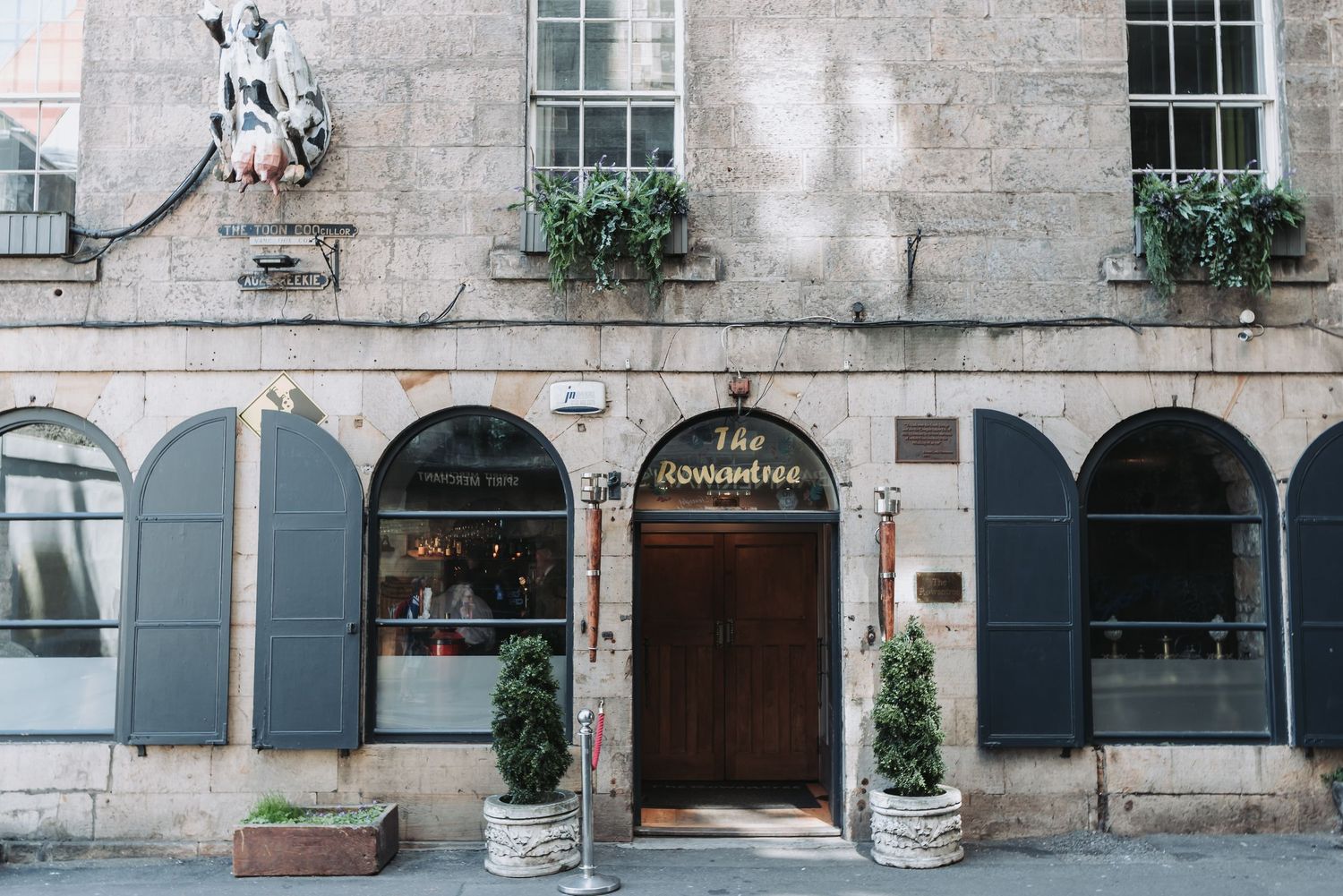 Historic stone building facade with blue-gray shuttered windows and arched doorways in Edinburgh's Old Town.