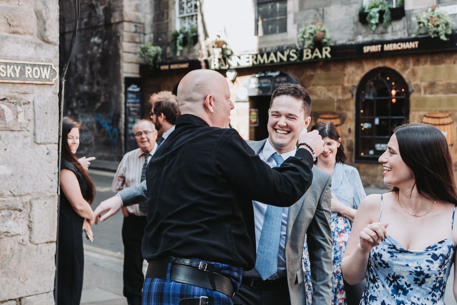 Festive gathering outside Scotsman's Bar with traditional Scottish attire and celebratory atmosphere.