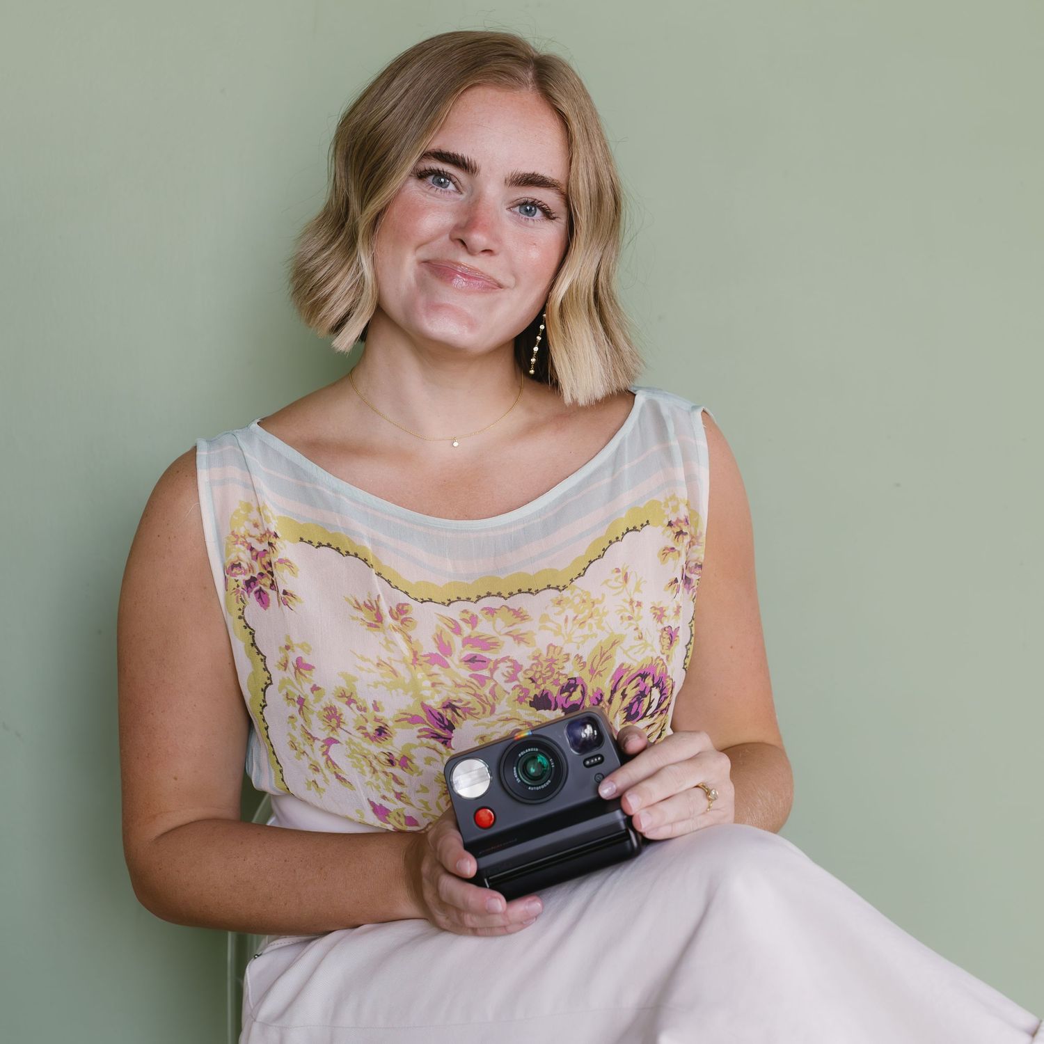 A black and white photo shows someone looking through an old camera while wearing a casual collared shirt.