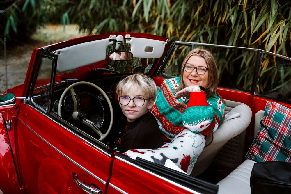 Mini-session photo de Noël 2024 avec une coccinelle VW rouge décorée pour les fêtes, créant une ambiance festive et chaleureuse.
