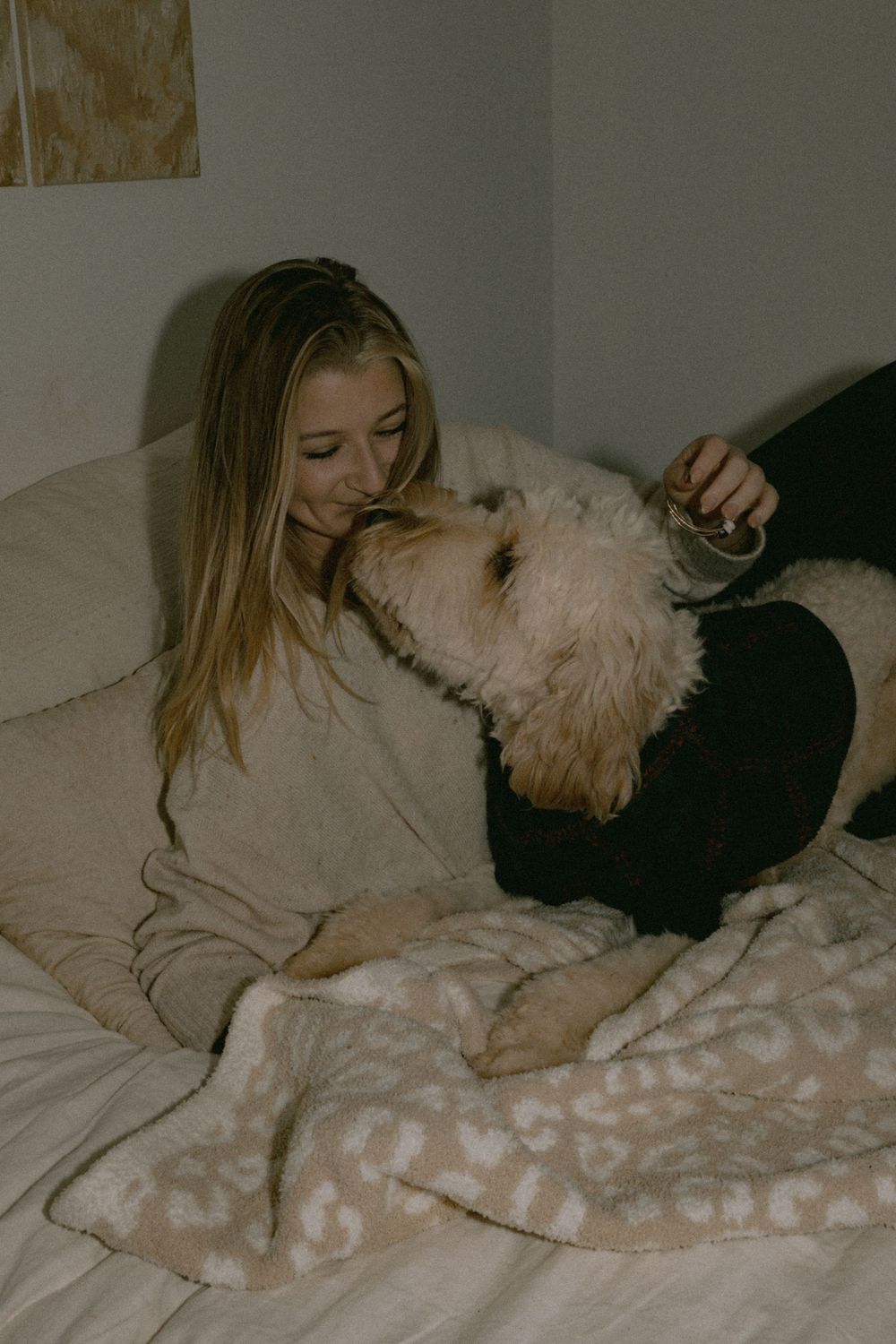 Person cuddling with white fluffy dog on cozy couch with blanket.