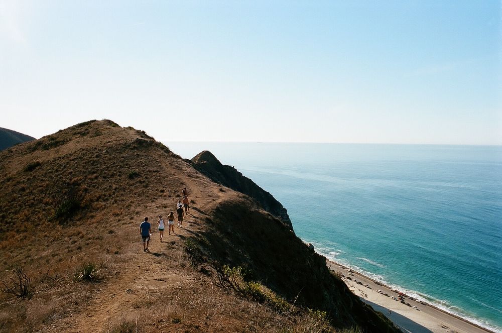 Hikers walking along a coastal trail overlooking the blue oceans of Malibu.