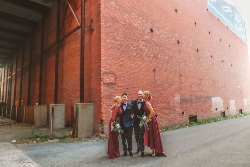 People stand against a long red brick wall in a series of photos showing different poses and groupings.