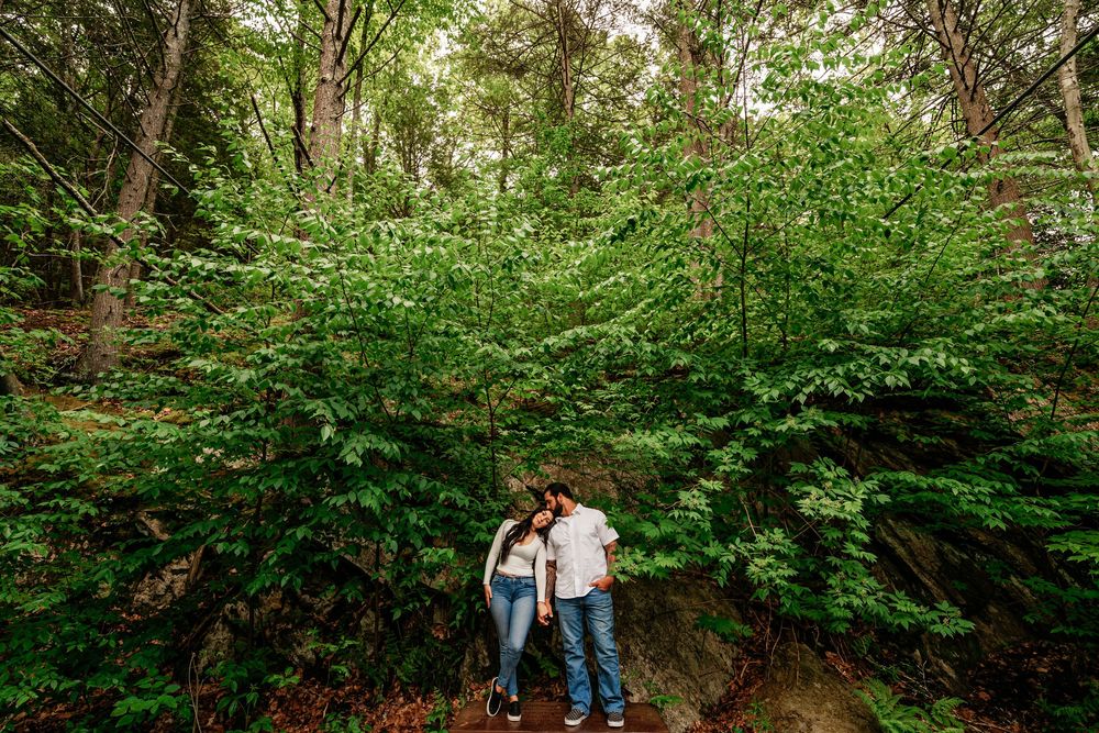 A couple walks together on a scenic forest trail surrounded by lush green foliage and natural scenery.