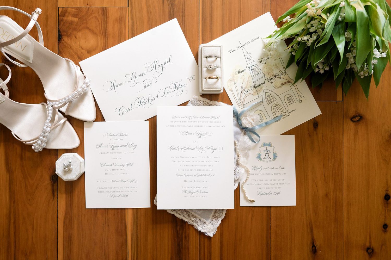 Wedding stationery and invitation suite arranged on wooden surface with greenery accents.