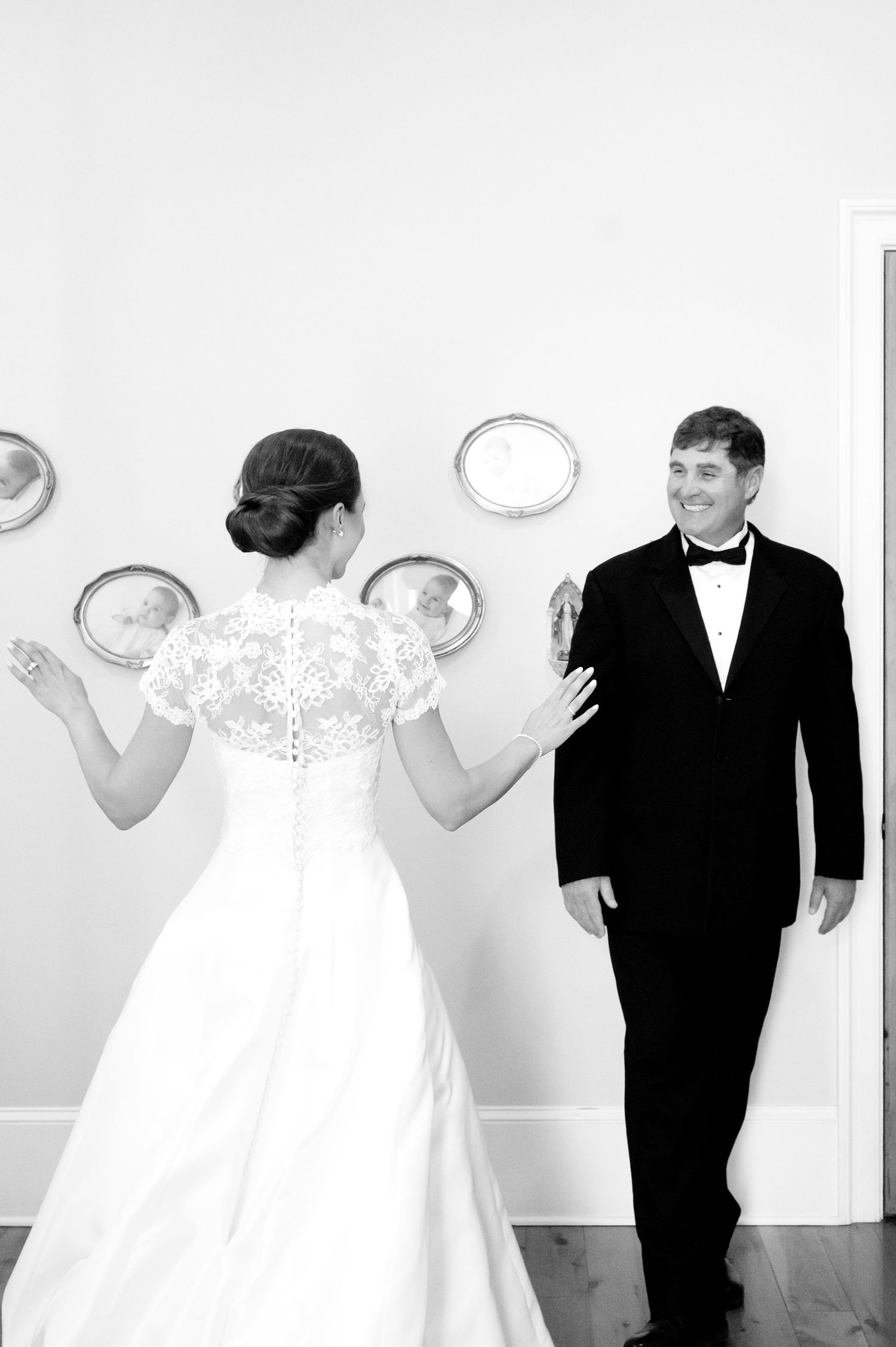 Black and white wedding portrait showing couple in formal attire with decorative wall plates.