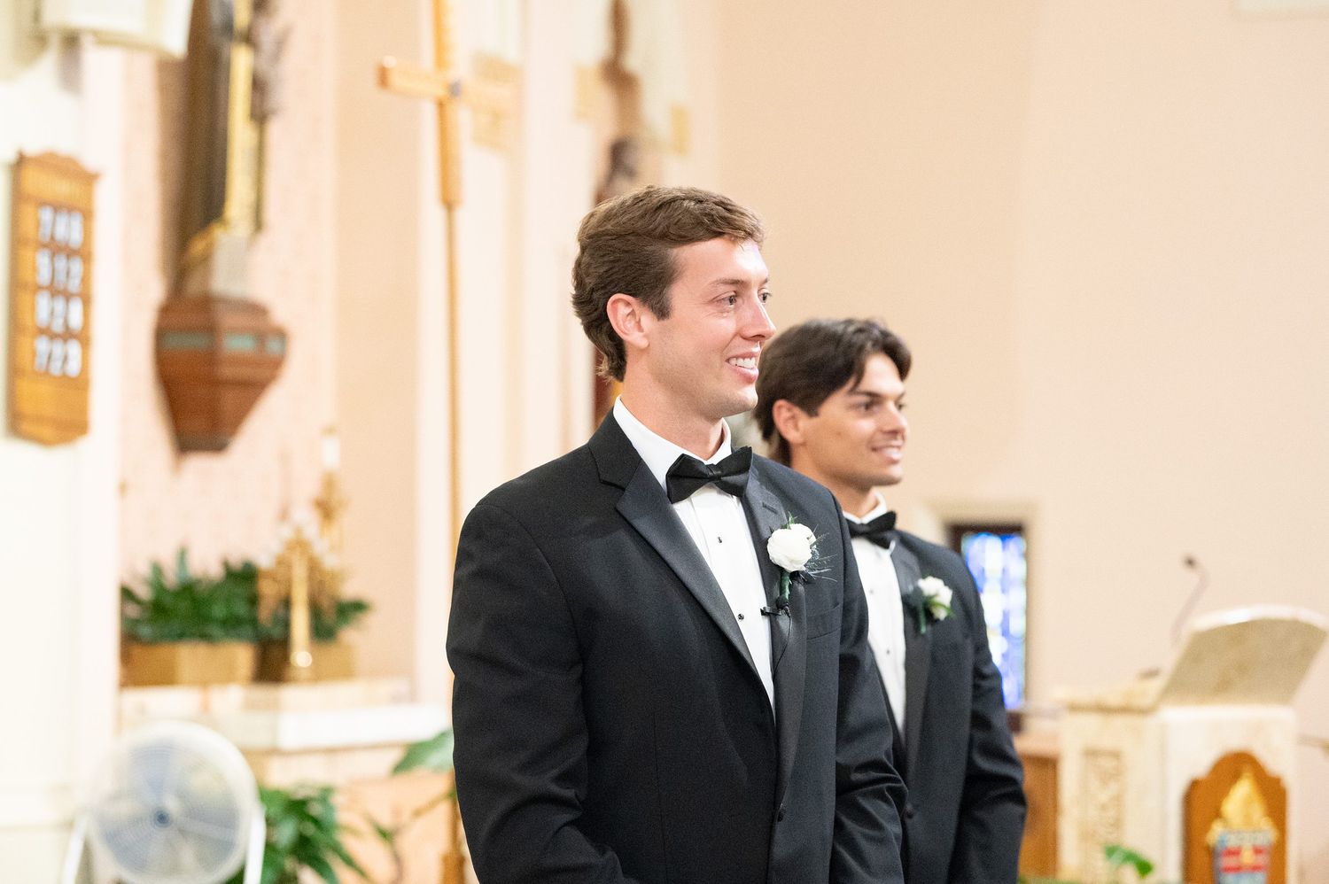 Elegant church interior with cream colored walls and wooden details during wedding ceremony.