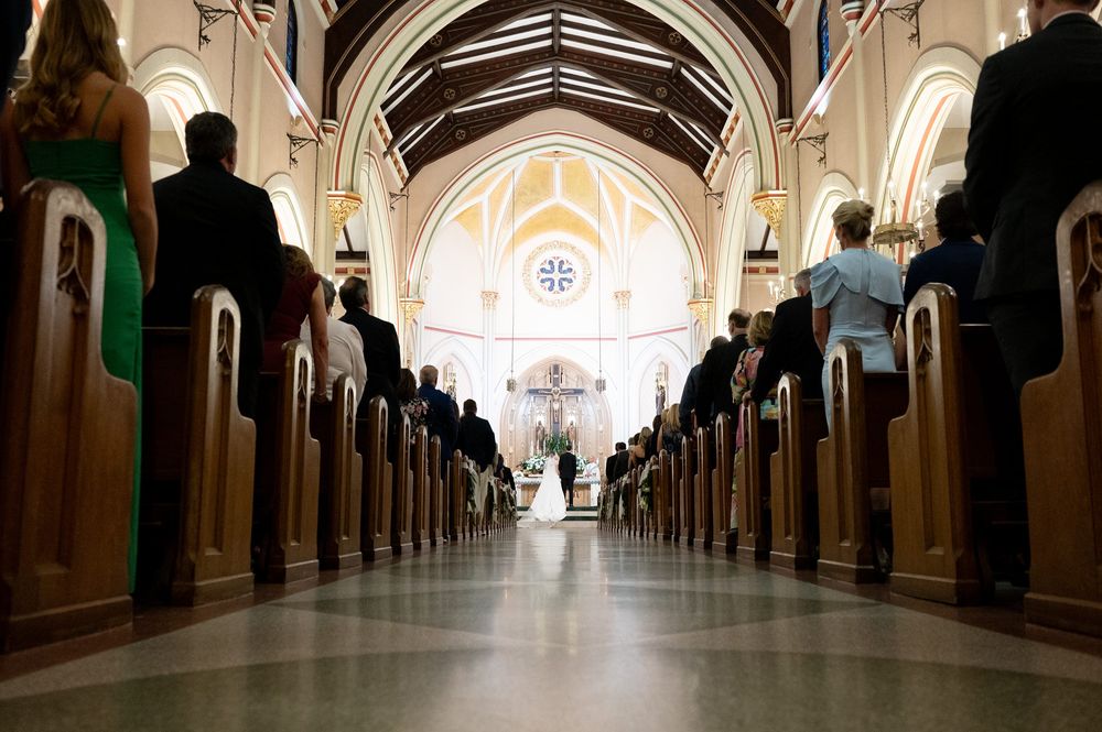 Elegant church interior with vaulted ceilings and wooden pews illuminated by natural light during a wedding ceremony.