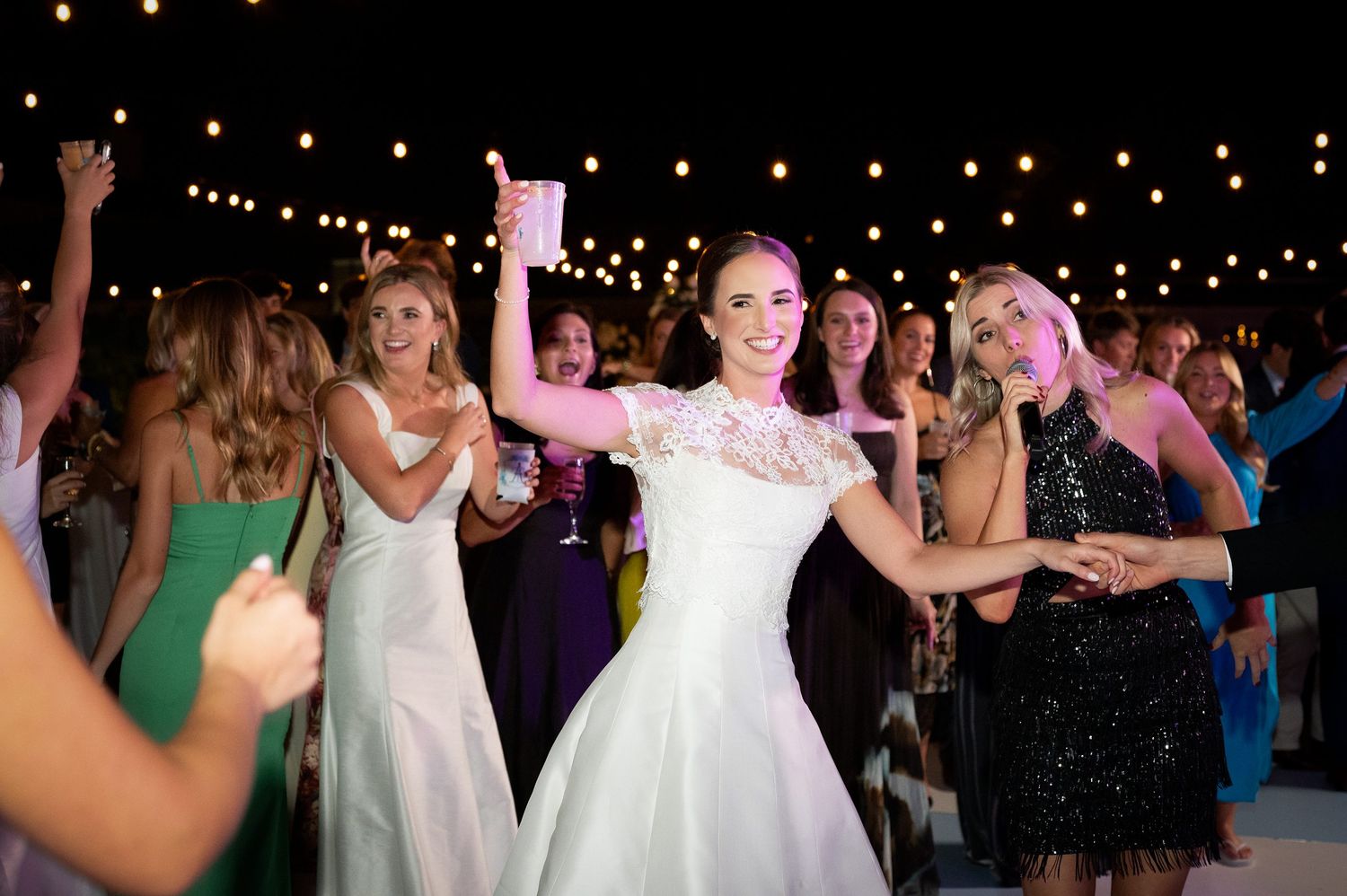 Festive wedding celebration with string lights and dancing guests.