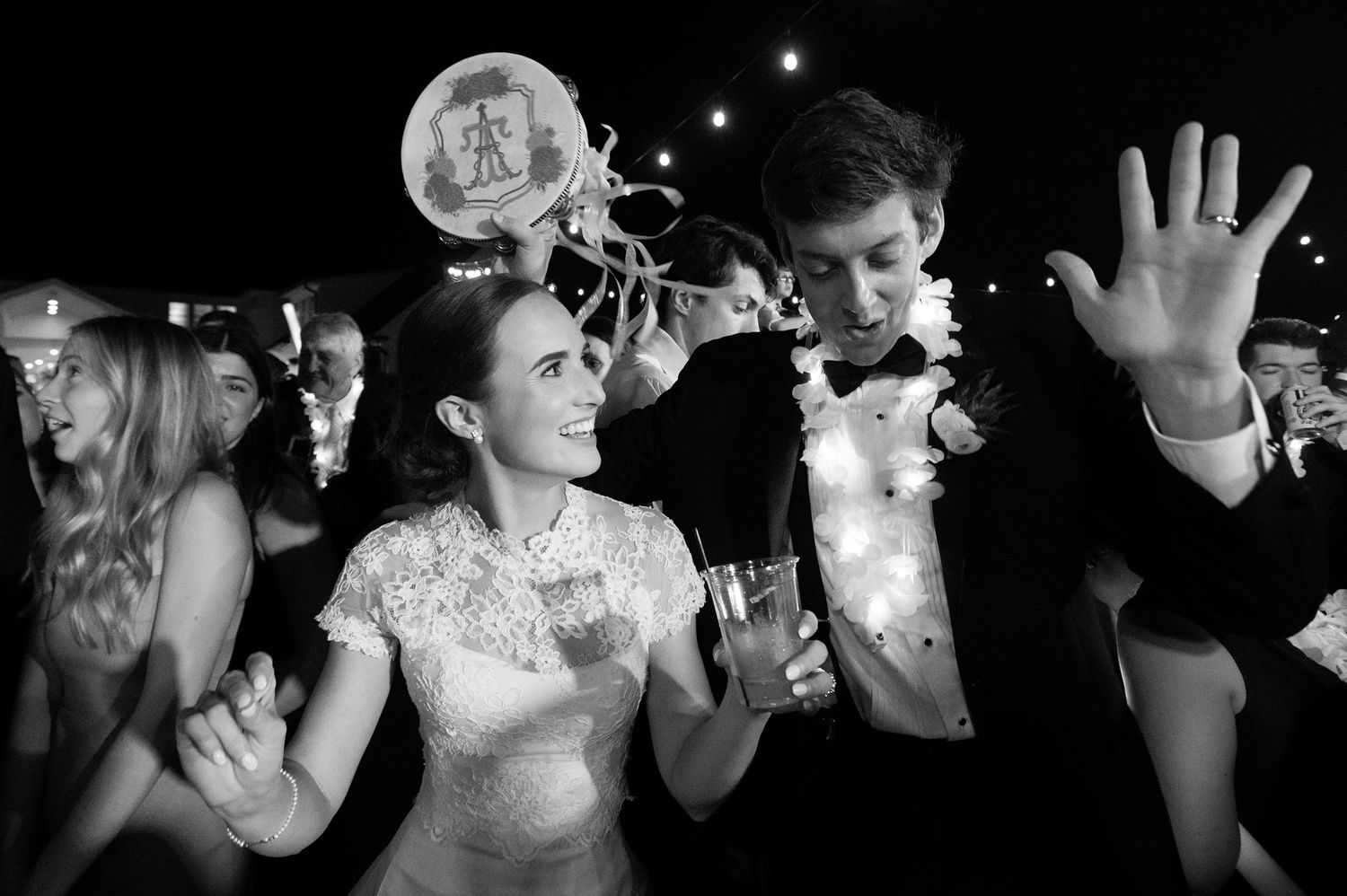 Wedding guests dancing and having fun on a dark dance floor with dramatic lighting.
