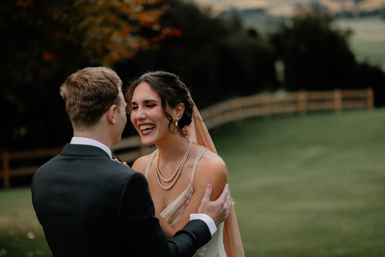 A couple shares intimate moments during their outdoor wedding photoshoot in a lush green field.