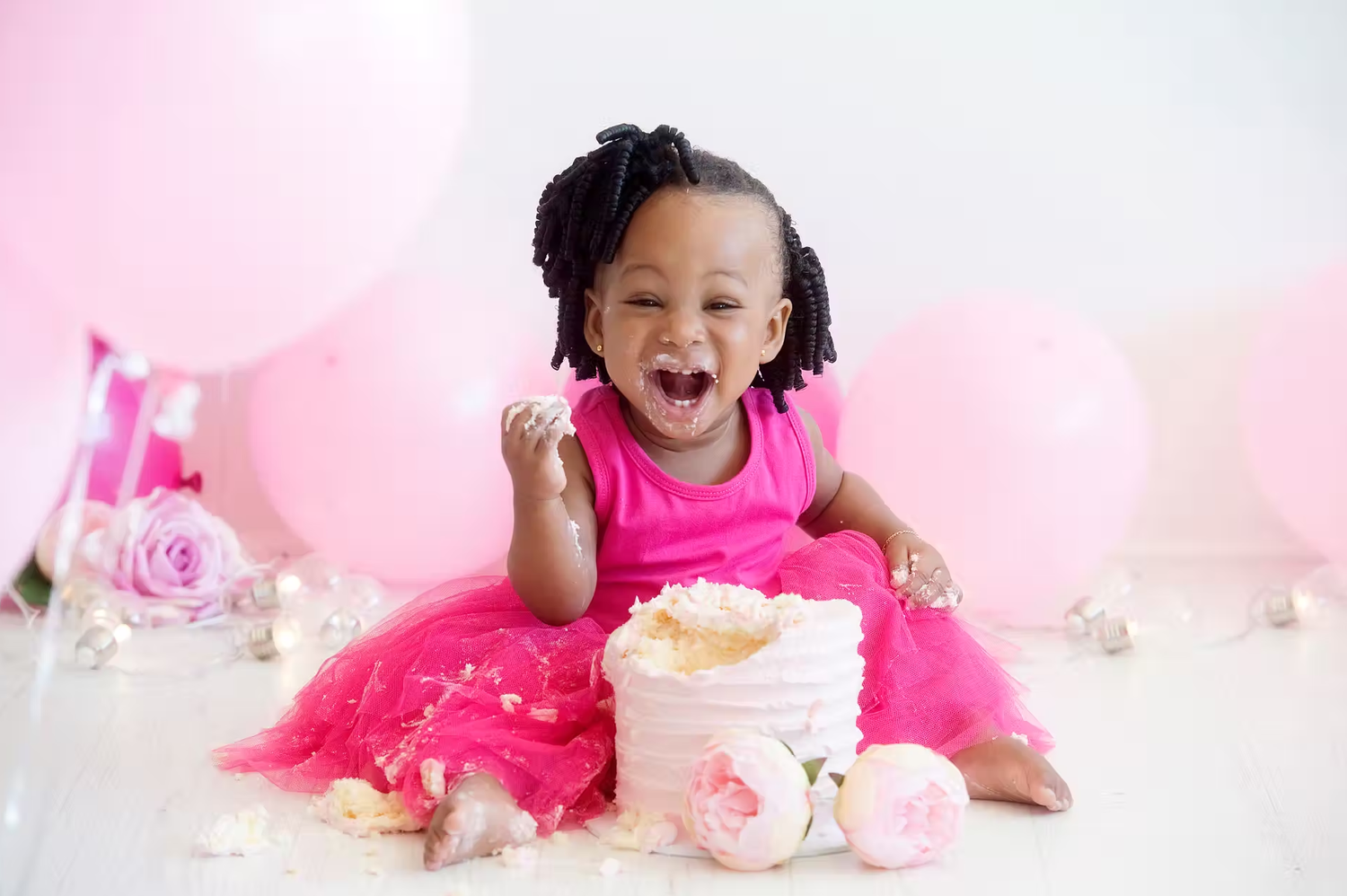 Baby girl in hot pink tutu dress during first birthday cake smash photography session.