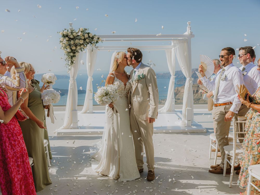 Joyful wedding celebration with white canopy and flower arrangements overlooking coastal views.