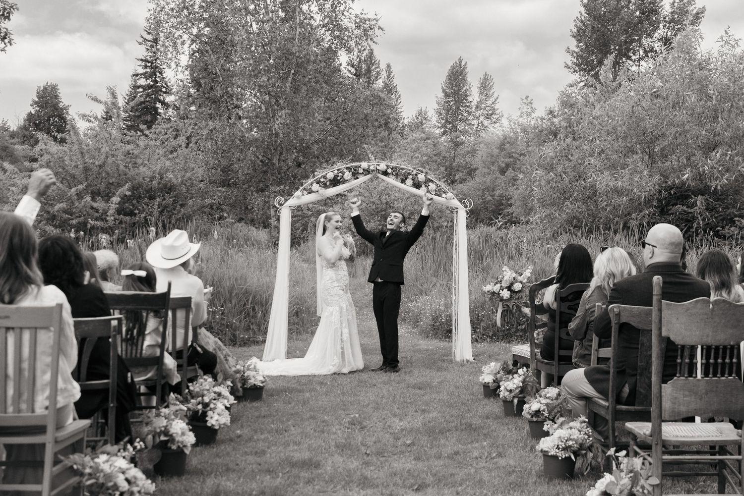 A black and white photo of a couple celebrating after the wedding ceremony, at Sadie Lake Events, Captured by Savvy Photography