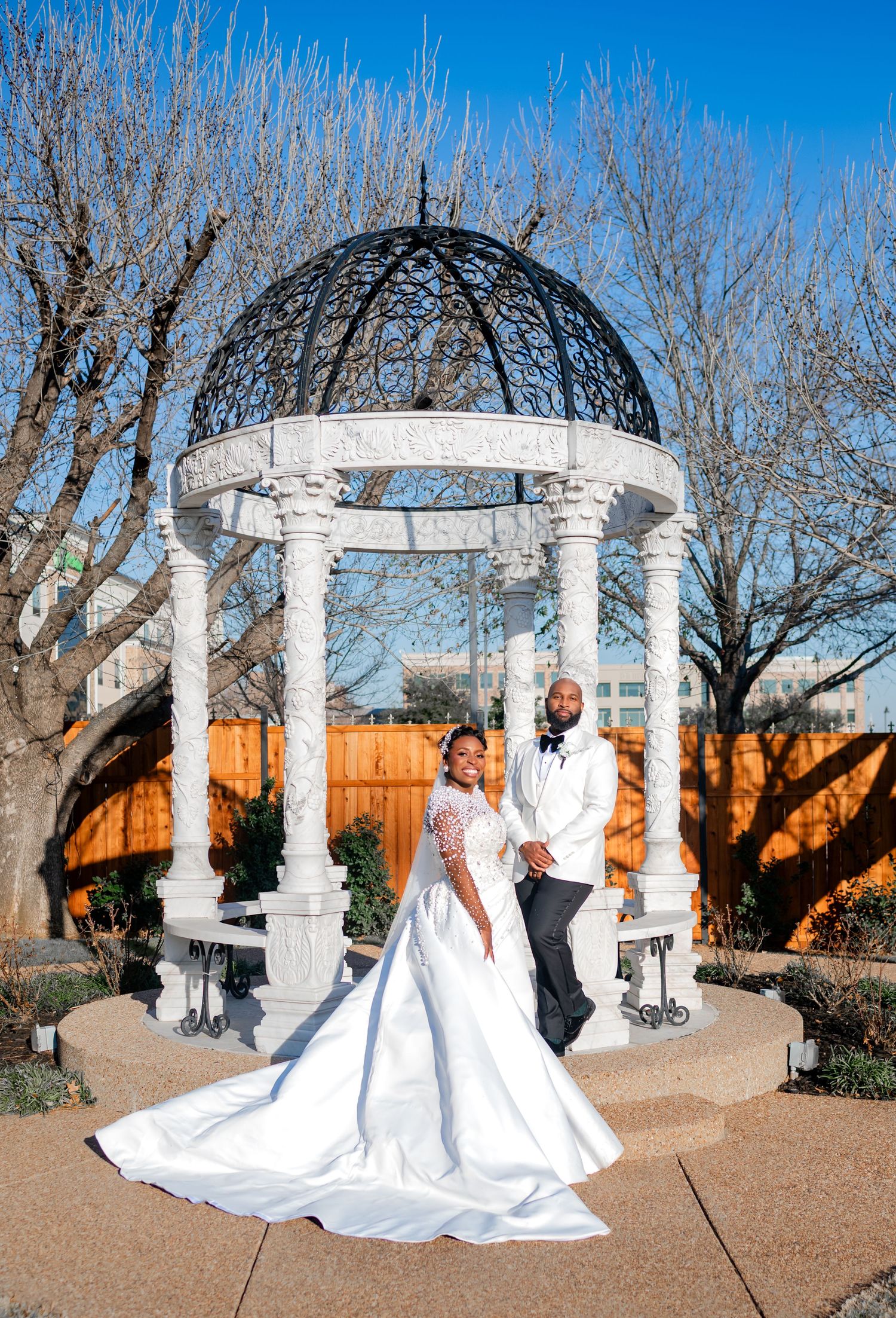A romantic wedding portrait showing a couple walking together on a lawn in front of a stately venue.